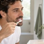 Man gently brushing his teeth as part of daily care for bleeding gums.